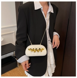 Detailed view of white semi-circular shoulder bag with golden wavy metal accessory