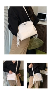 Detail of cream PU tote bag featuring decorative long tassels and unique cutout handle