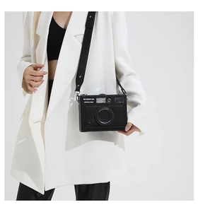 Detail of camera-shaped crossbody bag featuring black lychee pattern leather and wide strap
