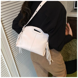 Close-up of cream PU tote bag featuring side tassels and adjustable wide shoulder strap