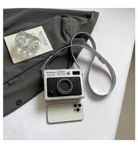 Detail of camera-shaped crossbody bag with silver-black textured leather and influencer text
