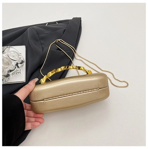 Detail showing elegant gold wavy metal handle and fine snake chain on the evening box bag
