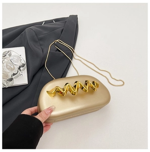Detail of matte gold hard shell evening bag with wavy handle and chain strap