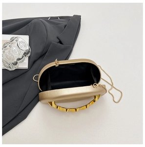 Detail of champagne gold evening bag showing wavy metal handle and black fabric lining