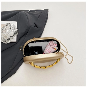 Detail view of gold oval evening clutch showing interior capacity for phone and makeup