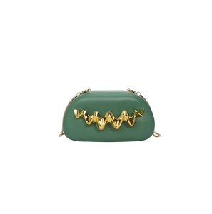 Detail of dark green handbag featuring unique gold wave metal trim and slim chain strap