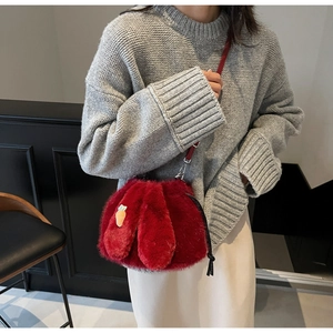 Detail of red plush bucket bag with cute bunny ears and a carrot pin accessory