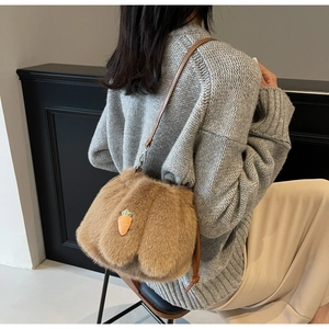 Detail of plush brown bucket bag featuring a carrot patch and soft faux fur texture