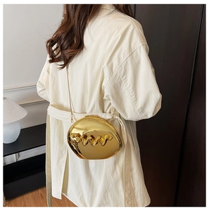 Macro shot of a luxury gold metallic evening bag with wavy texture and fine chain strap