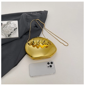 Detail of gold metal clutch with wavy shell texture next to a smartphone for size