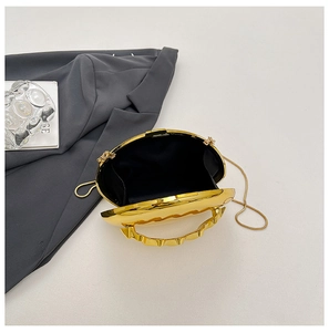 Detailed macro view of the gold evening bag featuring a wavy handle and internal chain