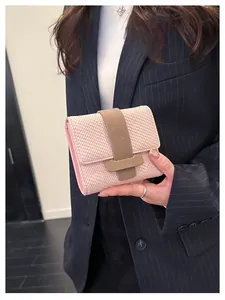Detail of pink bifold wallet with woven texture and brown magnetic strap closure