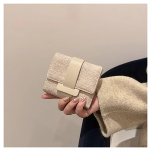 Detail of hand-held beige tweed trifold wallet featuring stylish leather buckle closure