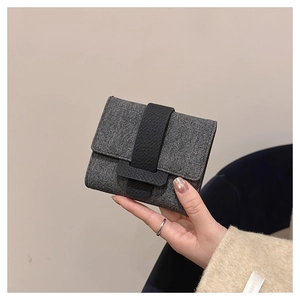 Close-up of grey textured fabric wallet with black leather flip buckle in hand