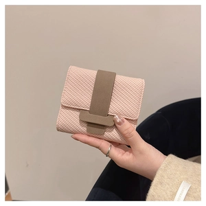 Close-up of pink fabric textured wallet with khaki T-bar closure held by hand