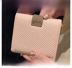 Close-up of light pink PU leather wallet showing diagonal texture and brown buckle strap