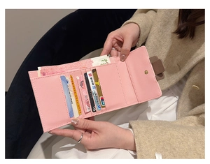 Pink faux leather tri-fold wallet detail showing multiple card slots and cash pocket