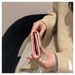 Close-up of pink tri-fold wallet with multiple card slots held by a model in a coat