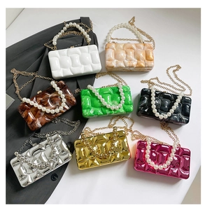 Flat lay of acrylic marble evening bags with pearl handles and gold chain straps