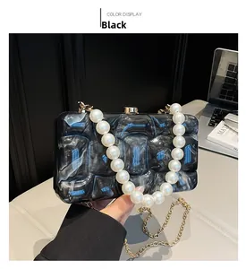 Detail of black marble acrylic evening clutch with pearl handle and gold chain strap