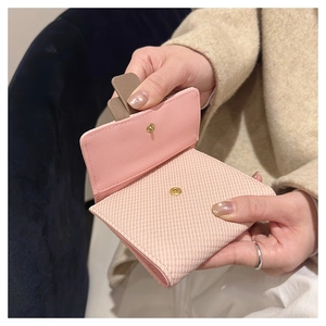 Close-up of light pink short wallet with cross-grain leather texture and gold snap button