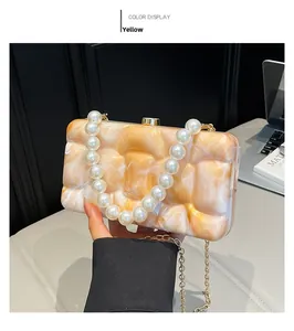 Detail of yellow marble acrylic clutch bag with pearl handle and gold chain strap