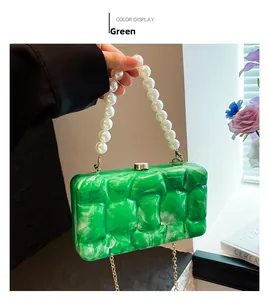 Detail of green acrylic clutch featuring marble texture and elegant pearl handle strap