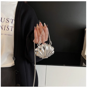 Detail of silver shell-shaped metallic crossbody bag with fine chain and textured finish