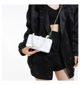 Close-up of a white acrylic box bag with quilted design and elegant pearl handle strap