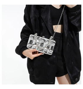 Detail of silver metallic acrylic evening bag featuring quilted wave texture and bead handle