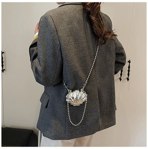 Detail of silver metallic shell crossbody bag worn with dark grey blazer for women