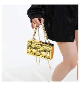 Detail of a luxury gold wavy evening clutch with metallic beads handle and chain strap