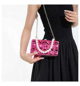 Detail of rose pink quilted clutch with pearl handle and gold chain strap on black dress