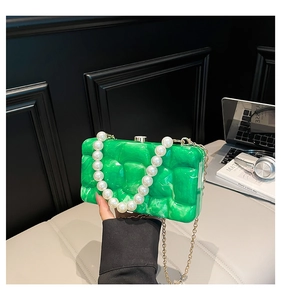 Detail of green marble acrylic evening bag with pearl handle and gold metal chain strap