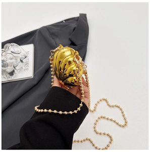 Close-up of golden metallic shell-shaped mini bag with high-gloss mirror finish and bead chain