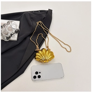 Detailed close-up of a metallic gold shell shaped mini bag with beaded chain and radial texture
