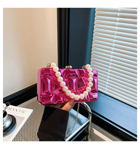 Detail of rose pink metallic clutch with square texture and large pearl handle strap