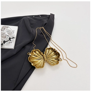 Detail of golden shell-shaped evening bag featuring metallic texture and chain strap