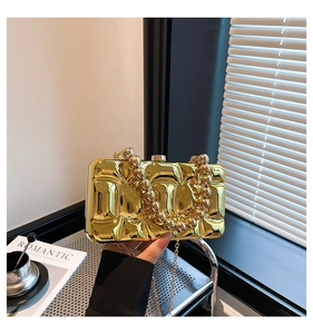 Detailed view of a gold metallic evening clutch with quilted texture and bead handle