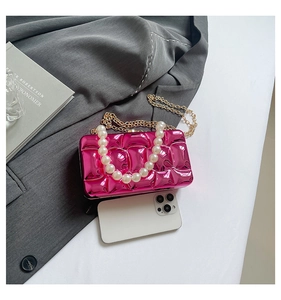 Detail of rose red metallic wavy evening bag with pearl handle and golden chain strap