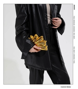 Close-up of a metallic gold shell-shaped clutch bag with glossy pleated finish details