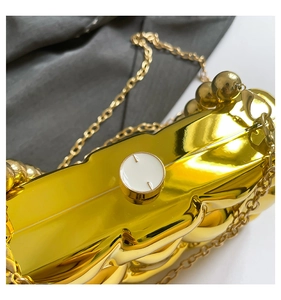 Detail of gold acrylic wave texture evening clutch bag with metallic chain and round clasp