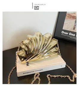 Detail view of light gold shell-shaped acrylic clutch bag with metal chain strap