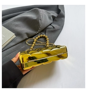 Detail of gold evening clutch featuring wave texture, pearl handle, and metal clasp