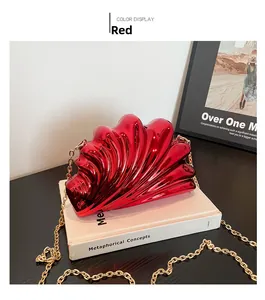 Close-up of a red shell-shaped acrylic clutch with gold chain and pleated texture