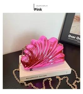 Detail of pink acrylic shell clutch with metallic finish and gold chain strap