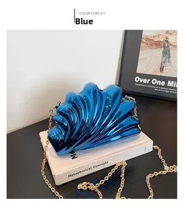 Detail of blue shell-shaped evening clutch with metallic finish and gold chain strap