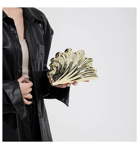 Close-up of golden shell-shaped evening clutch with mirrored metal finish and textures