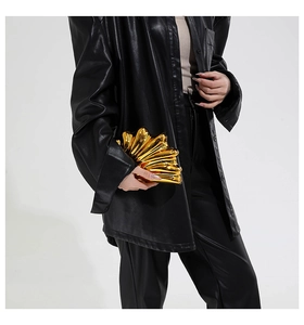 Macro detail of a golden shell-shaped evening clutch bag with artistic metallic texture