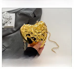 Close-up of golden heart-shaped clutch with hammered texture and metal chain strap